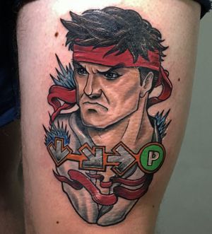 Get your game on with this new school illustrative tattoo featuring Ryu unleashing a powerful Hadouken attack, expertly done by artist Jethro Wood on your upper leg.