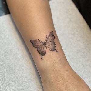 Elegantly detailed black and gray butterfly tattoo on the forearm by artist Sophie Rose Hunter.