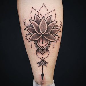 Elegant dotwork and fine line lotus flower tattoo by Fernando Joergensen, beautifully placed on the lower leg.