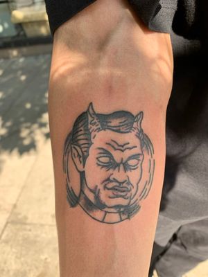 Get a striking black and gray devil tattoo on your forearm in London. This traditional illustrative design will make a bold statement.