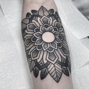 Elegant black and gray dotwork forearm tattoo featuring a stunning ornamental mandala flower design by artist Lamat.