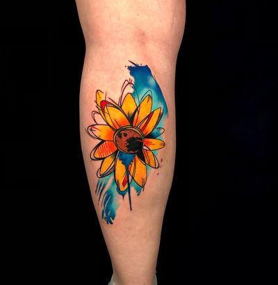 Get a burst of color with this new school watercolor sunflower tattoo on your lower leg by artist Sandro Secchin.