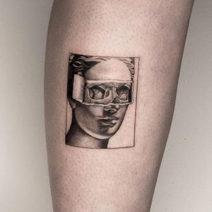 A detailed black and gray illustration of a woman with stylish glasses, beautifully tattooed on the lower leg by Oek.
