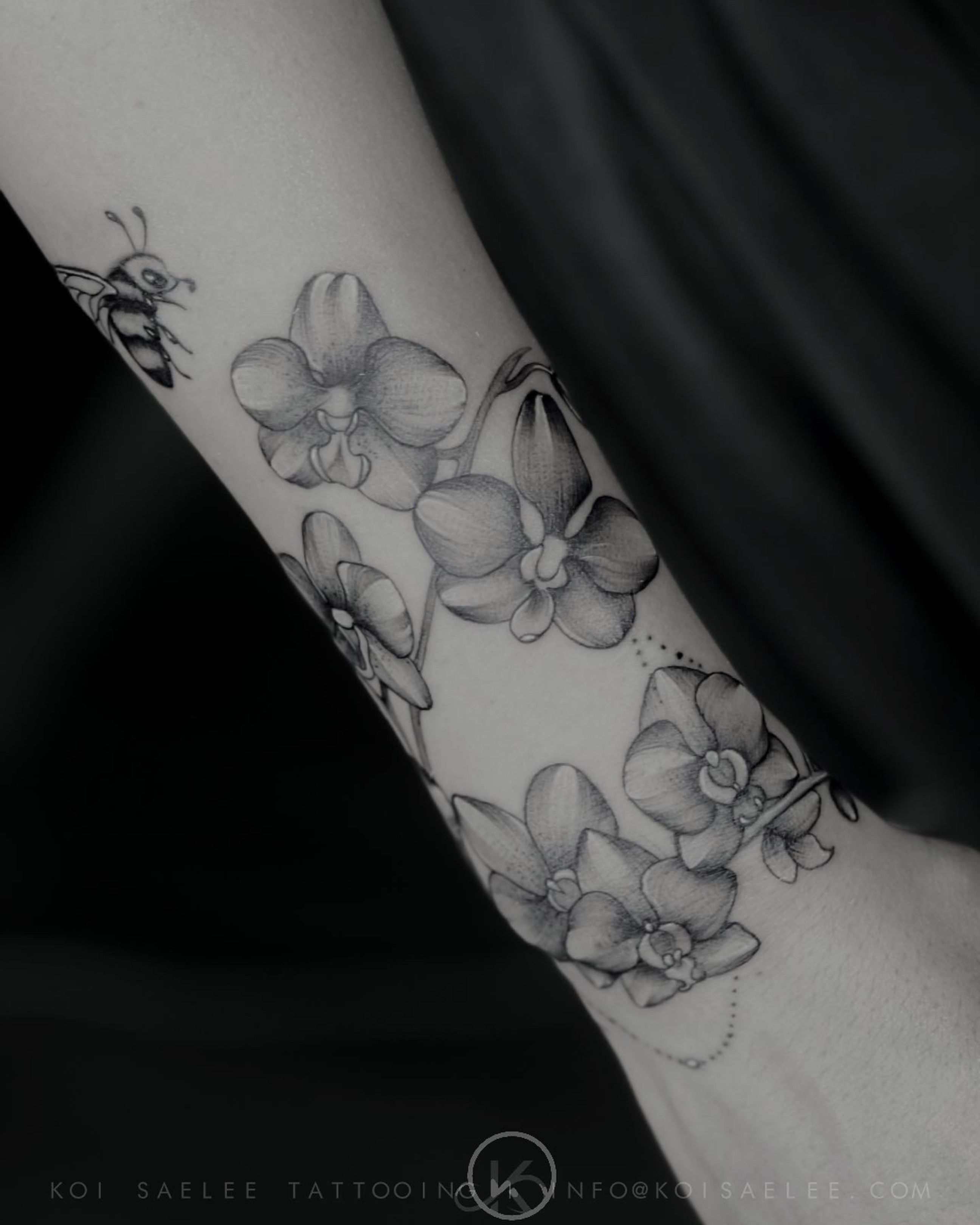 Small orchid branch tattoo on the left inner forearm.