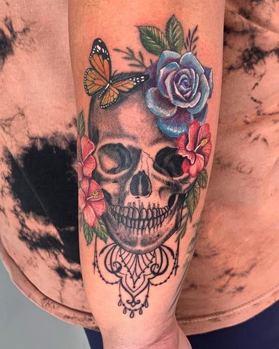 Vibrant butterfly, flower, and skull design beautifully blended in watercolor style on forearm by renowned artist Brigid Burke.