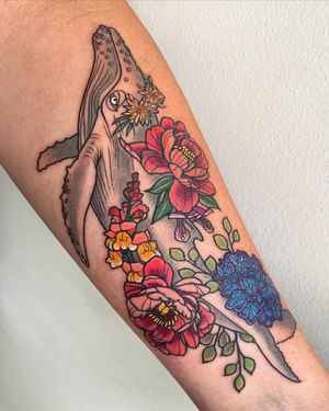 A stunning neo-traditional tattoo by artist Brigid Burke featuring a majestic whale swimming amongst delicate flowers on the forearm.