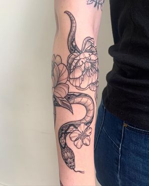 Illustrative blackwork tattoo by Brigid Burke featuring a snake and flower motif. Perfect for forearm placement.