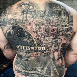 Experience the bold contrast of blackwork and trashpolka styles coming together in this back piece featuring a fierce bear and iconic Hollywood buildings by artist Jake Masri.