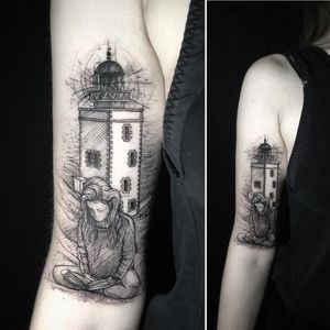 This black and gray fine line tattoo on the upper arm features a captivating lighthouse, a mystical girl, intricate sketchwork, and a book. By talented artist Aygul.