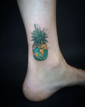 Unique and colorful ankle tattoo featuring a pineapple and map design, beautifully done by tattoo artist Aygul.