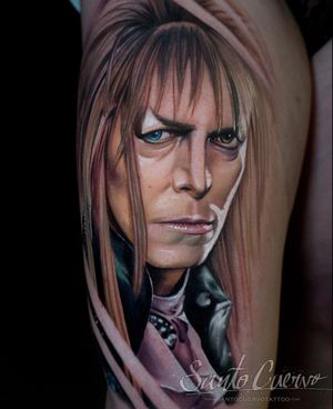 Get a stunning David Bowie tattoo on your upper leg by artist Alex Santo, capturing the iconic musician in lifelike detail.