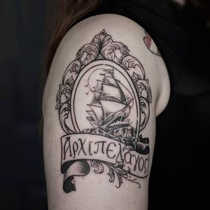 Stunning black and gray upper arm tattoo by Luca Salzano featuring a detailed ship, delicate filigree, and elegant lettering.