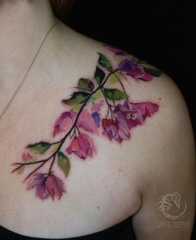 Vibrant watercolor flower tattoo on shoulder, expertly done by Alex Santo. A stunning and colorful masterpiece.
