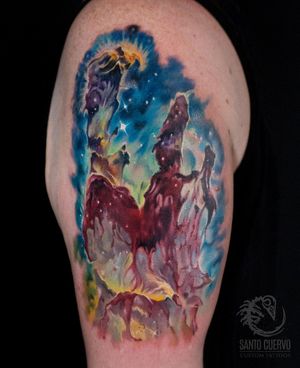 Experience a stunning blend of watercolor and surrealism with this mesmerizing galaxy tattoo on your upper arm. Created by the talented artist Alex Santo.