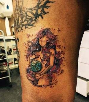 Beautiful upper leg tattoo featuring a watercolor world design symbolizing maternal love, by artist Frankie Brown.