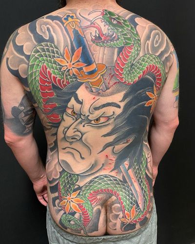 A stunning tattoo featuring a snake, sword, namakubi, and dripping blood, expertly done in Japanese illustrative style by artist Daniel Werder.