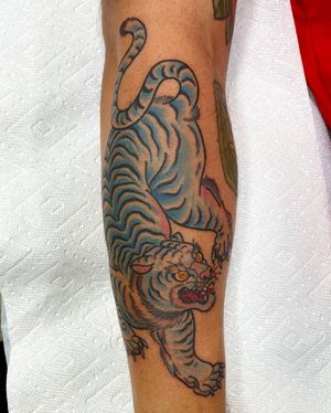 Embrace the power and beauty of Japanese art with this fierce tiger tattoo on your shin, expertly crafted by tattoo artist Daniel Werder.