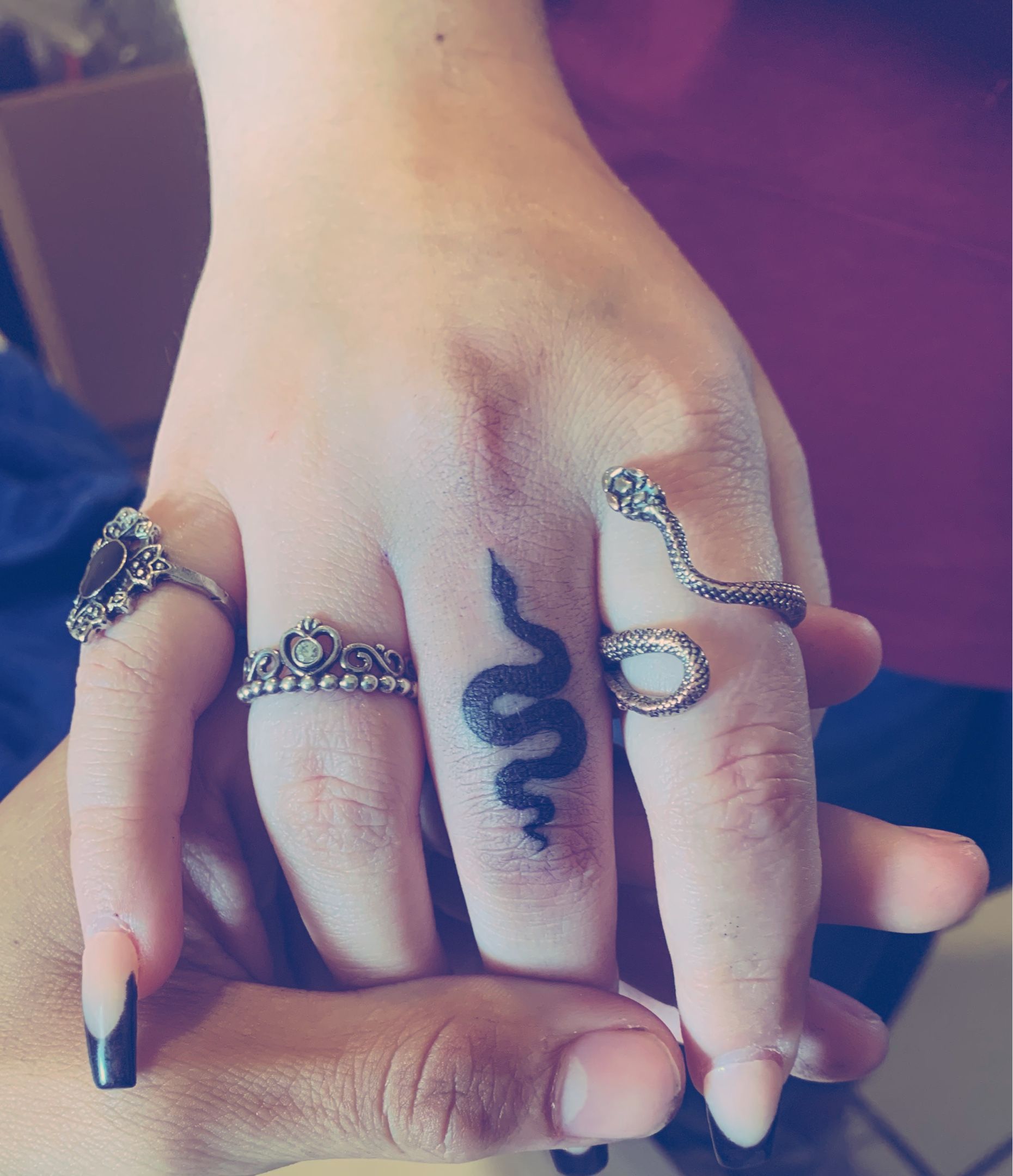 Minimalist snake tattoo on the finger.