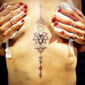 Stunning ornamental tattoo of lotus flower and unalome design on sternum, beautifully crafted by Frankie Brown.