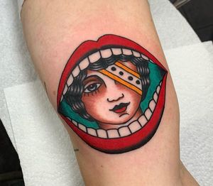 Get a striking traditional tattoo featuring a woman with lips, teeth, and mouth on your arm in London, GB.