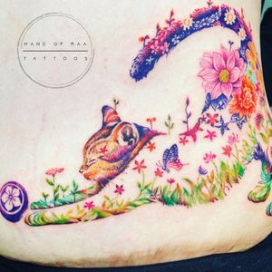Get a stunning watercolor tattoo on your ribs featuring a cat and flower design by the talented artist Raa.
