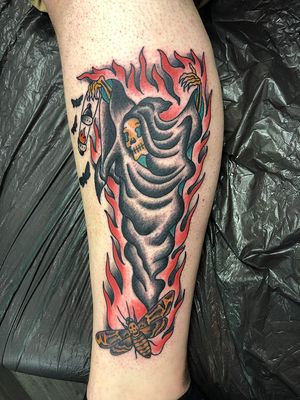Embrace your mortality with this illustrative traditional tattoo featuring a grim reaper surrounded by flames, done by the talented artist Shawn Nutting.