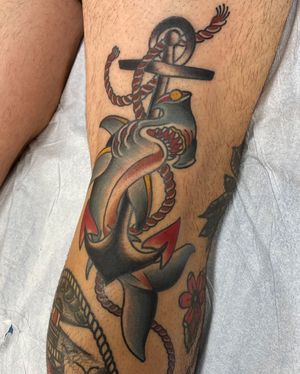 Get a bold traditional tattoo of a shark, anchor, and rope on your knee in Los Angeles for a timeless and classic look.