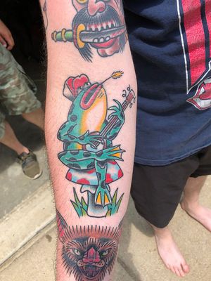 Beautiful Japanese style tattoo featuring a frog playing guitar on forearm. Created by renowned artist Shawn Nutting.