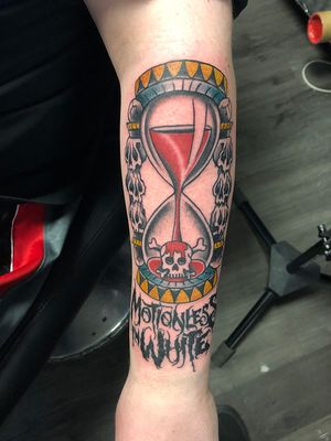 Traditional design by Shawn Nutting for the forearm, combining skull and hourglass motifs.