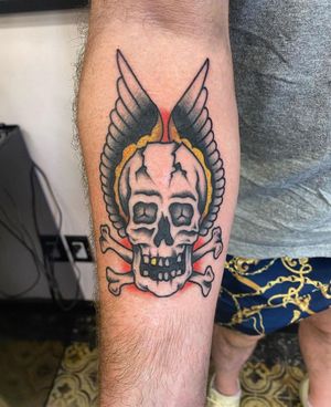 Get a classic traditional skull with wings tattoo on your forearm in Los Angeles for a timeless and bold statement.