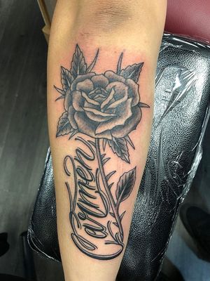 Get a stylish forearm tattoo by Shawn Nutting combining lettering and illustrative flower in blackwork style.