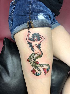 Get a stunning illustrative mermaid tattoo on your upper leg by the talented artist Shawn Nutting. Dive into a sea of creativity!