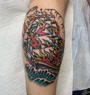 Get a fiery illustrative tattoo of a ship on your lower leg by the talented artist Andre Bertoncin. A bold and vibrant design that demands attention.