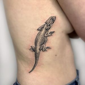 Stunning black & gray chameleon tattoo in white ink, perfect for rib placement in London, GB.