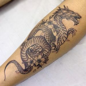 Get a stunning Japanese inspired tattoo with a fierce dragon and delicate sakura flowers on your forearm in London. Expertly crafted in traditional Japanese style.