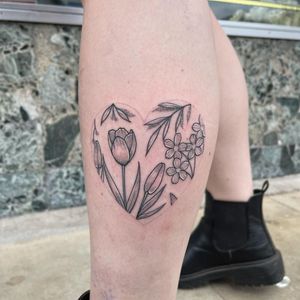 Beautiful lower leg tattoo by Chris Harvey featuring a delicate dotwork design of a heart surrounded by floral sprigs.