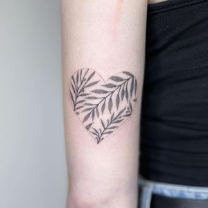 Grace your upper arm with a delicate dotwork design of intertwining branches, leaves, and heart symbol, expertly rendered by tattoo artist Chris Harvey.