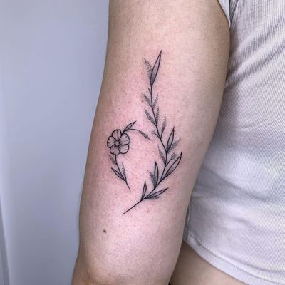 Beautifully detailed upper arm tattoo featuring a dotwork flower, sprig, and leaf design by talented artist Chris Harvey.