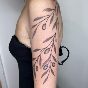 Beautiful flower and leaf design on upper arm by tattoo artist Chris Harvey. Intricate dotwork style with illustrative elements.
