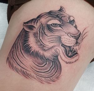 Experience the fierce beauty of a blackwork tiger tattoo by Dani Mawby, boldly displayed on your upper leg. Stand out with this striking piece of art.