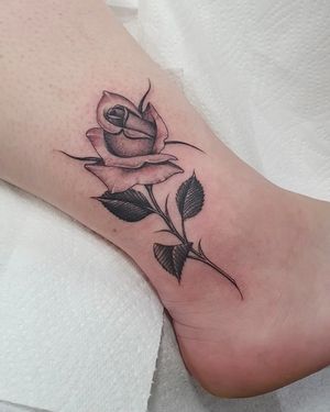 Elegant floral fine line rose tattoo on ankle in London, GB. Perfect for a delicate and feminine touch.