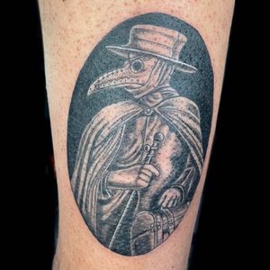 Illustrative forearm tattoo of a hat, mask, and Dr Plague in striking blackwork style by talented artist Michaelle Fiore.