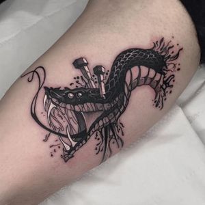 Get a bold and vibrant new school snake and nails design on your upper arm in London. Stand out with this unique tattoo!