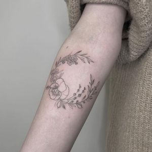 Get a beautiful fine line flower tattoo on your forearm in London, GB. Perfect for a subtle yet elegant look.