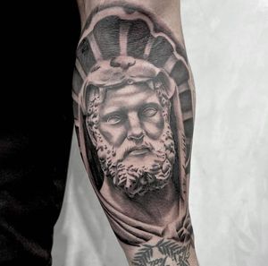 Get a bold blackwork tattoo of a bearded man statue on your forearm in Los Angeles. Stand out with this illustrative design.