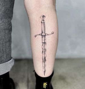 Unique blackwork dagger tattoo on lower leg, blending illustrative style in the heart of LA.