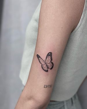 Get a stunning blackwork butterfly tattoo on your upper arm in Los Angeles for a unique and illustrative look.