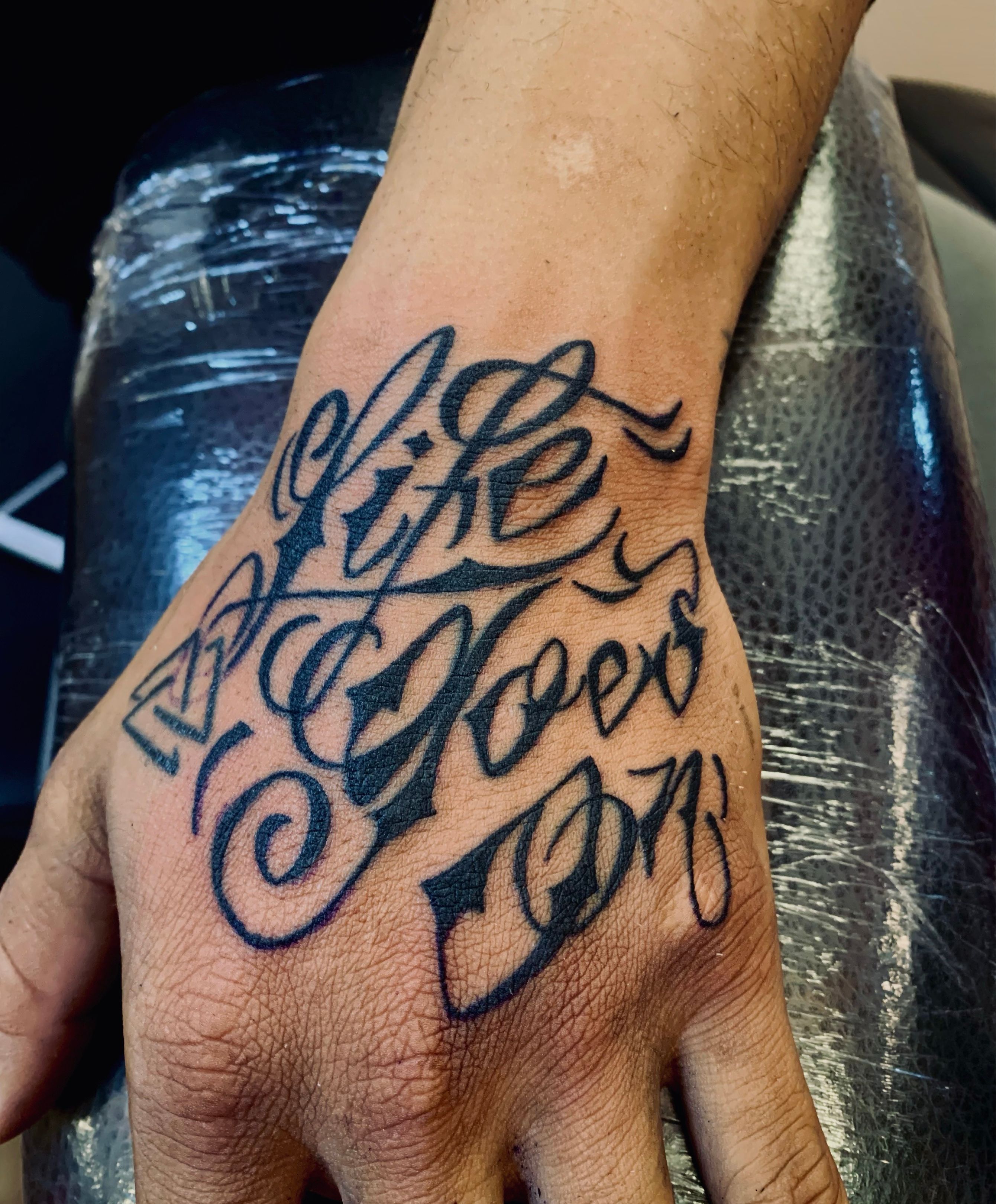 hand writing life goes on tattoo black and grey  Reds Tattoo