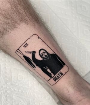 A striking blackwork tattoo on the lower leg, featuring death, a mask, a card, and a knife. By the talented Miss Vampira.