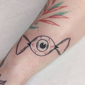 Illustrative forearm tattoo combining a sweet candy motif with a mystical eye design in London.